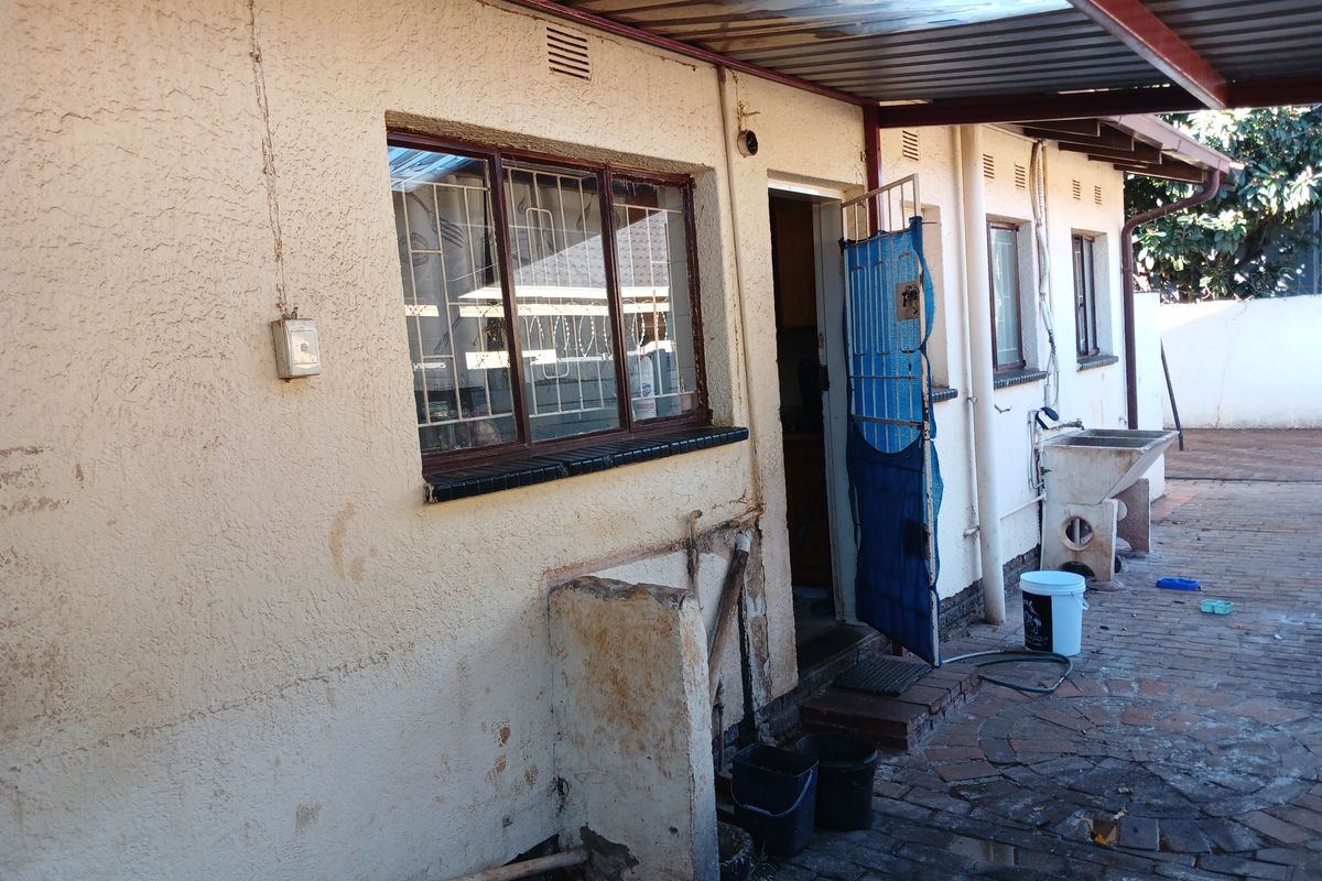 Rear exterior view of the property featuring a paved courtyard, covered patio area, and external utility sink.