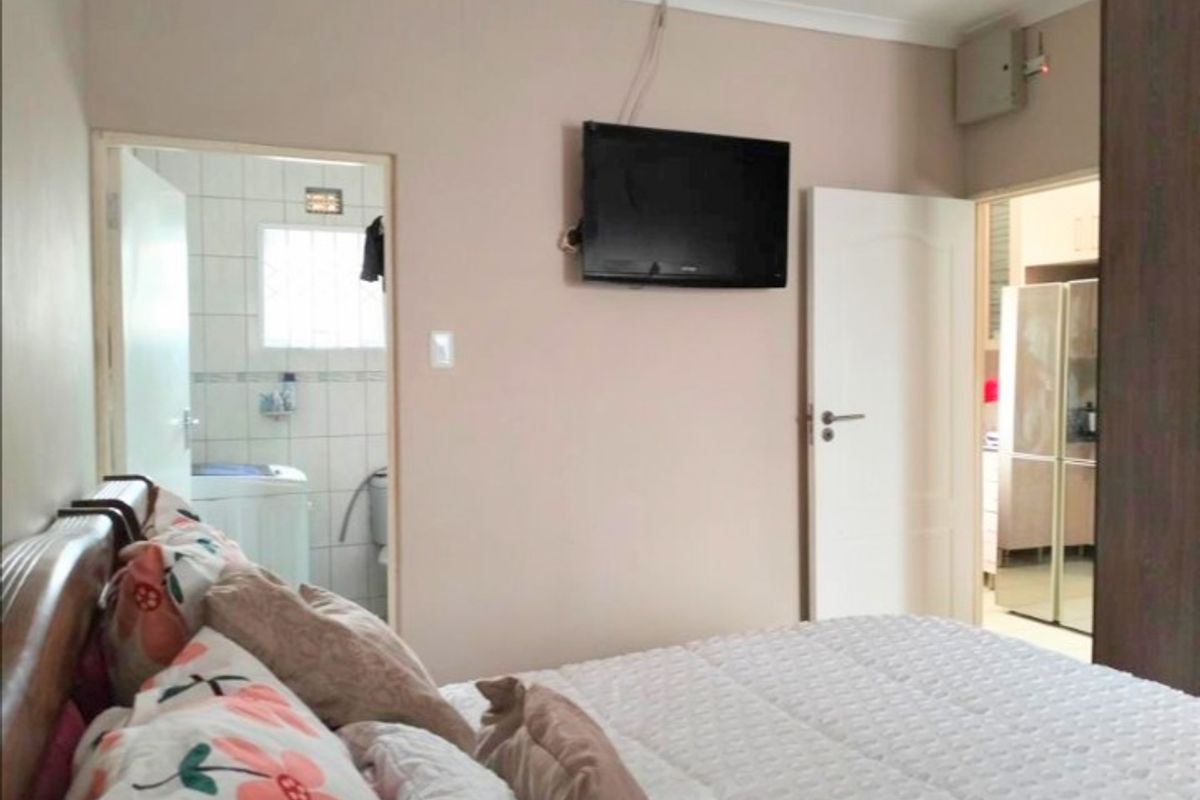 A bedroom featuring a built-in wardrobe, coving, and direct access to an en-suite bathroom, with visible electrical wiring above the wall-mounted television.