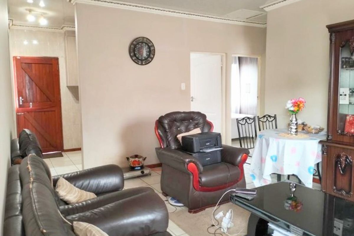 A living room area featuring tiled flooring and crown molding, providing a functional space with access to adjacent rooms.