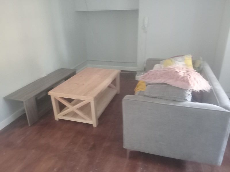 A living room area featuring an intercom system and wood-look flooring, currently furnished with basic seating and tables.