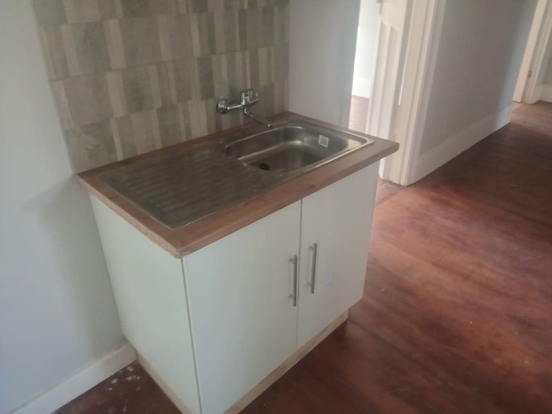 A compact scullery or utility area featuring a stainless steel sink, wooden countertop, and tiled splashback, suitable for a small apartment.