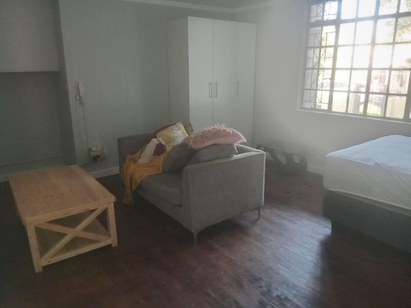 A bedroom featuring laminate flooring, a built-in wardrobe, and a large window with security bars.