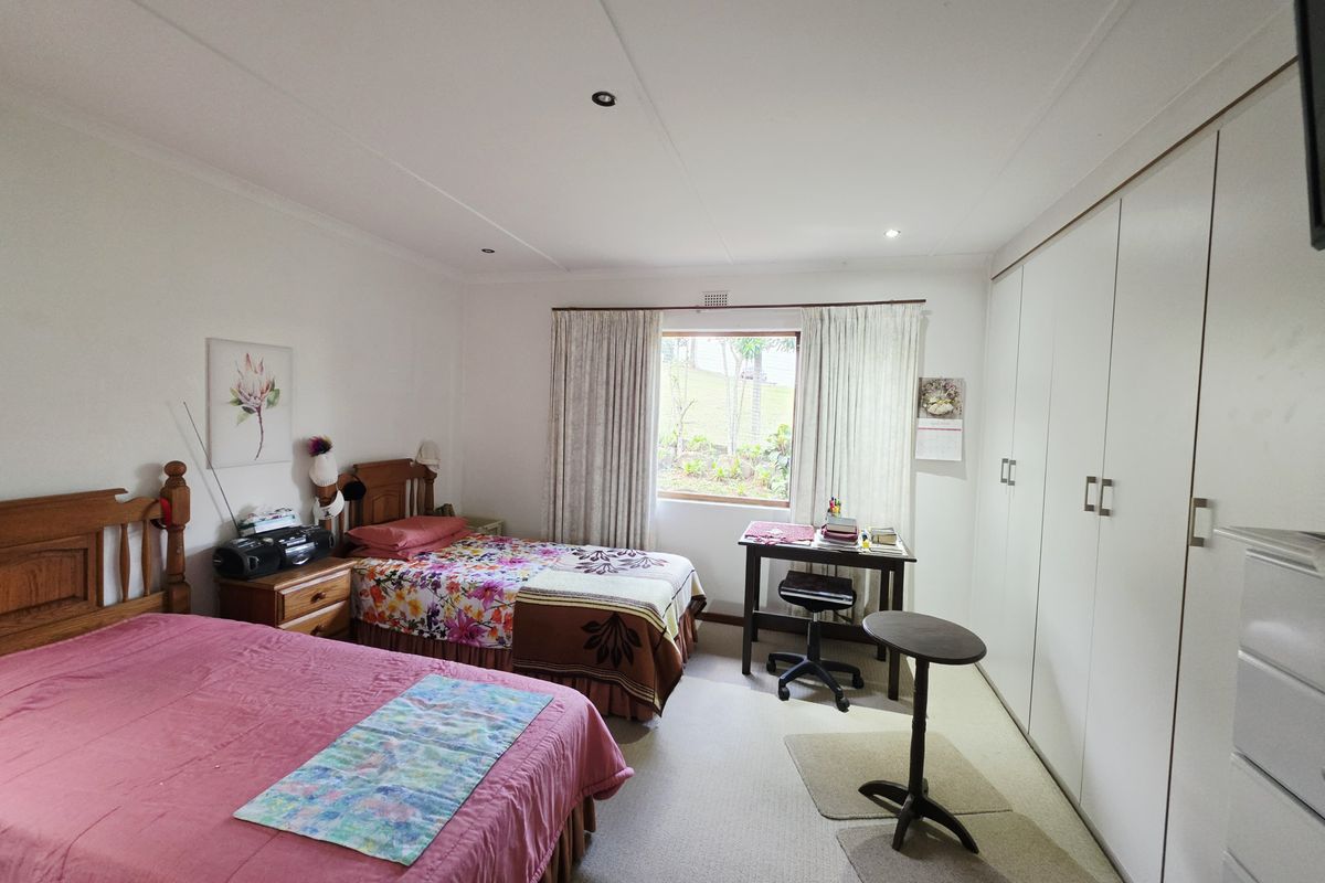 Spacious bedroom featuring built-in cupboards, neutral carpeting, and recessed downlighting, offering a functional layout with natural light from the window.