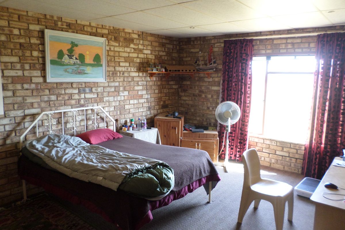 A bedroom featuring exposed brick walls, carpeted flooring, and a drop ceiling, offering a rustic aesthetic with potential for modernization.