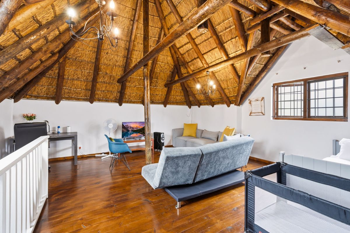 Spacious living area featuring a high vaulted thatched ceiling with exposed timber rafters and warm timber flooring.