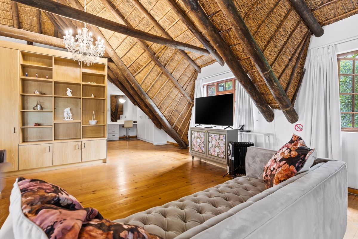 Spacious bedroom featuring a high vaulted thatched ceiling with exposed timber rafters, polished timber flooring, and custom built-in cabinetry.