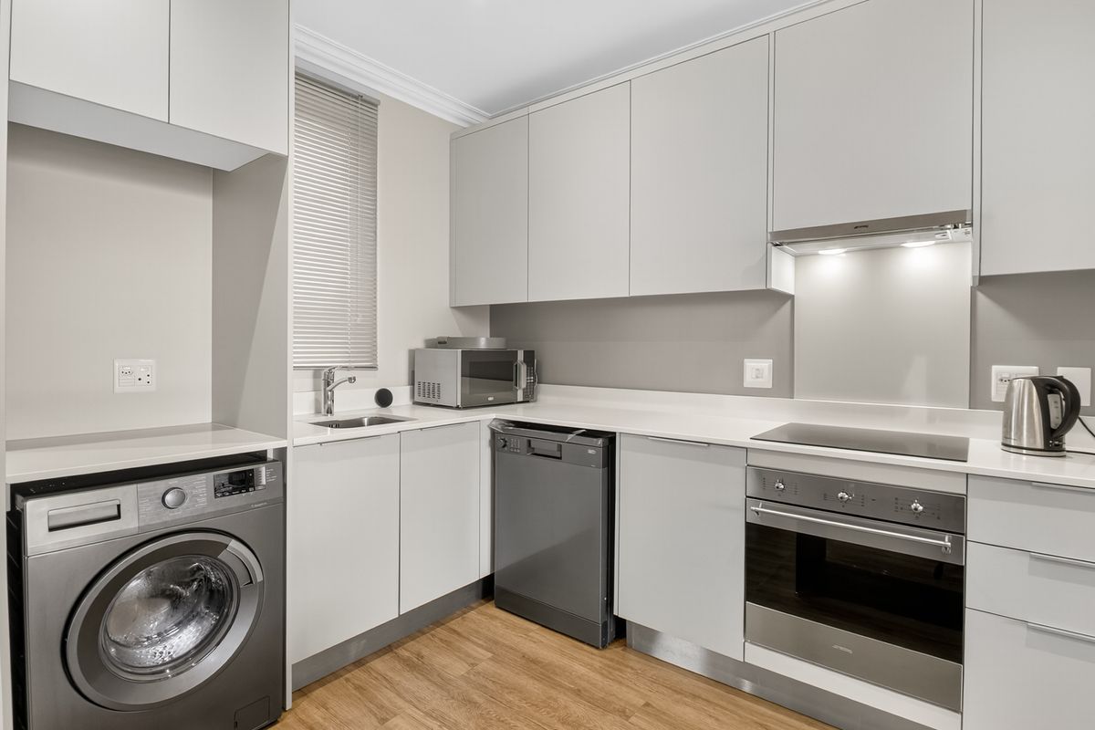 Modern kitchen featuring sleek grey cabinetry, stone countertops, integrated appliances, and high-quality finishes, providing a functional and contemporary culinary space.
