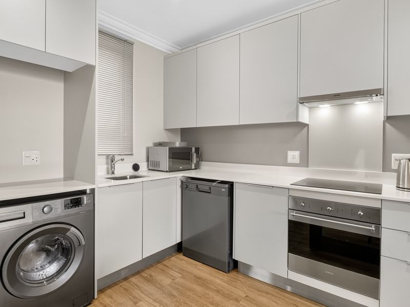 Modern kitchen featuring sleek grey cabinetry, stone countertops, integrated appliances, and high-quality finishes, providing a functional and contemporary culinary space.
