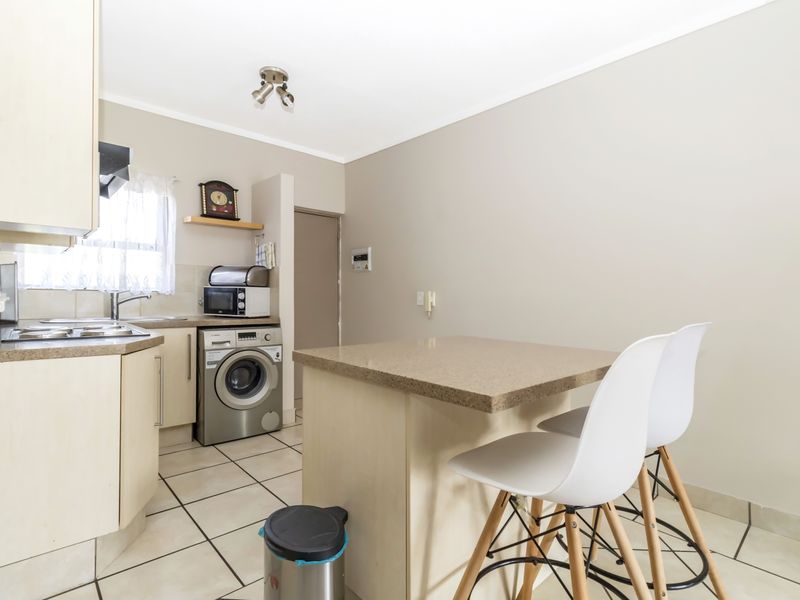Compact kitchen featuring built-in cabinetry, laminate countertops, a breakfast nook, and tiled flooring, providing a functional space for cooking and dining.