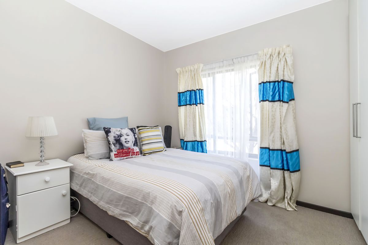 A well-lit bedroom featuring neutral wall tones, carpeted flooring, and a built-in wardrobe, providing a functional and comfortable living space.