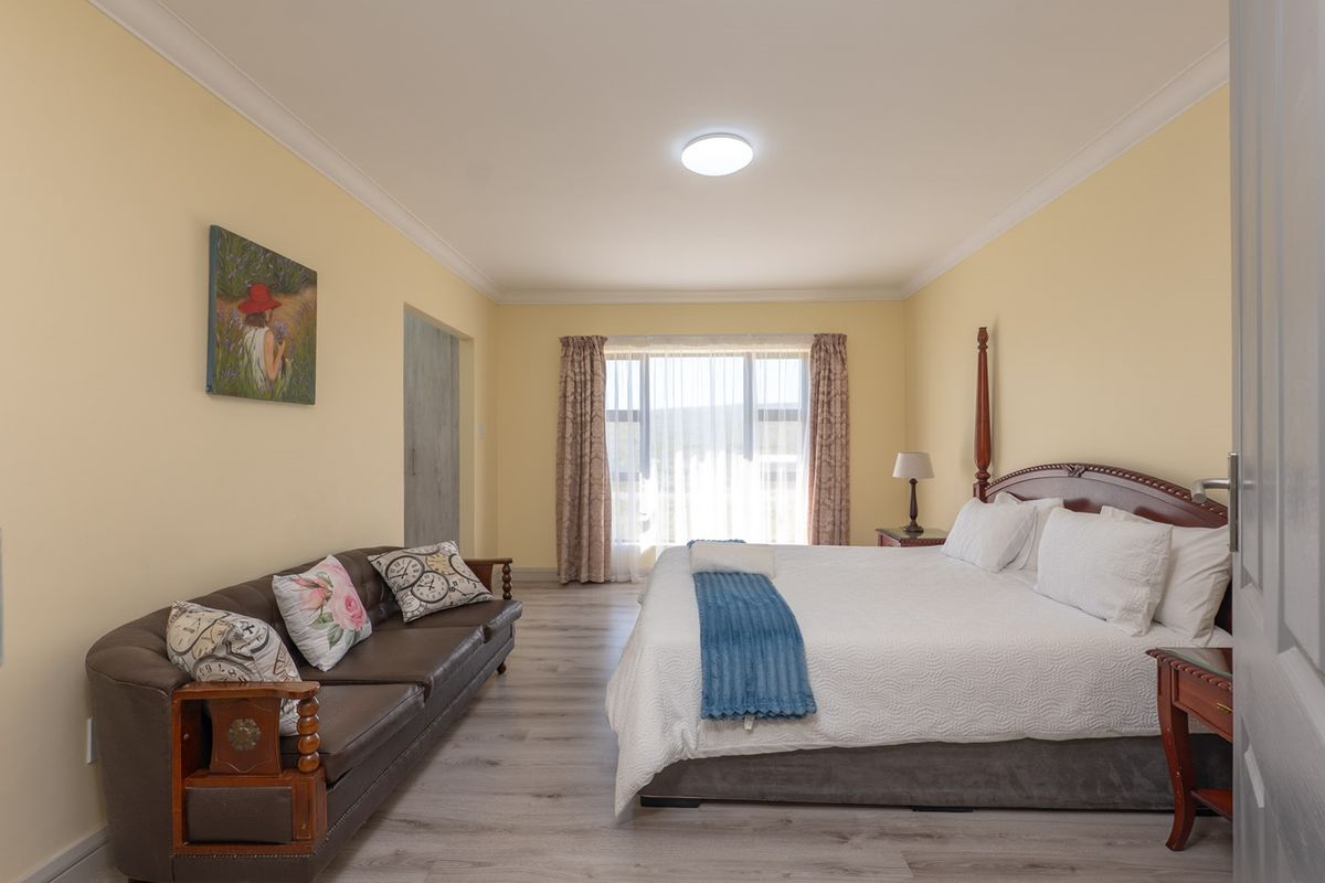 Spacious bedroom featuring light-toned laminate flooring, neutral walls, and a large window with natural light, providing a comfortable and functional living space.