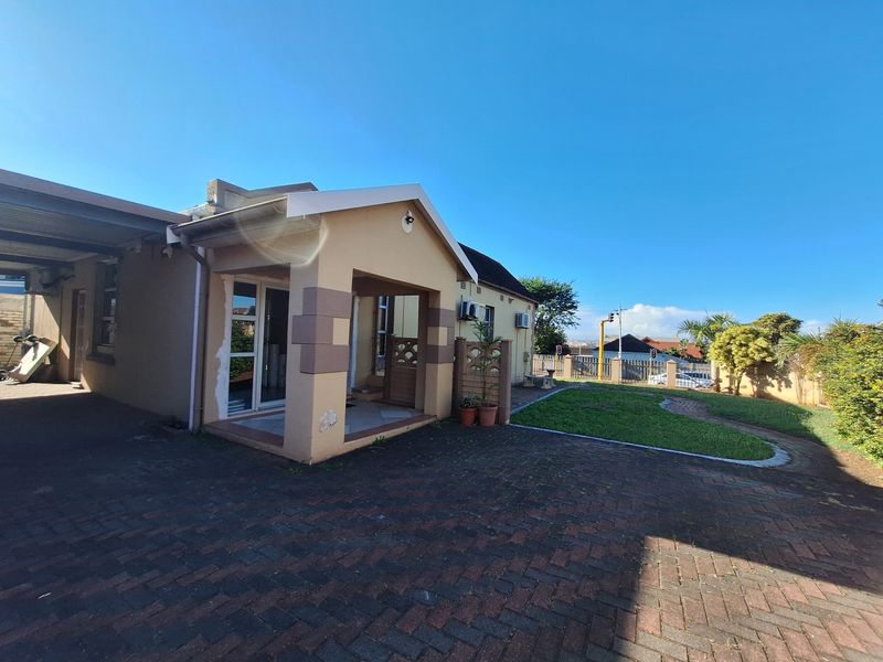 Exterior view of the house featuring a paved driveway, covered entrance porch, and a small landscaped garden area.