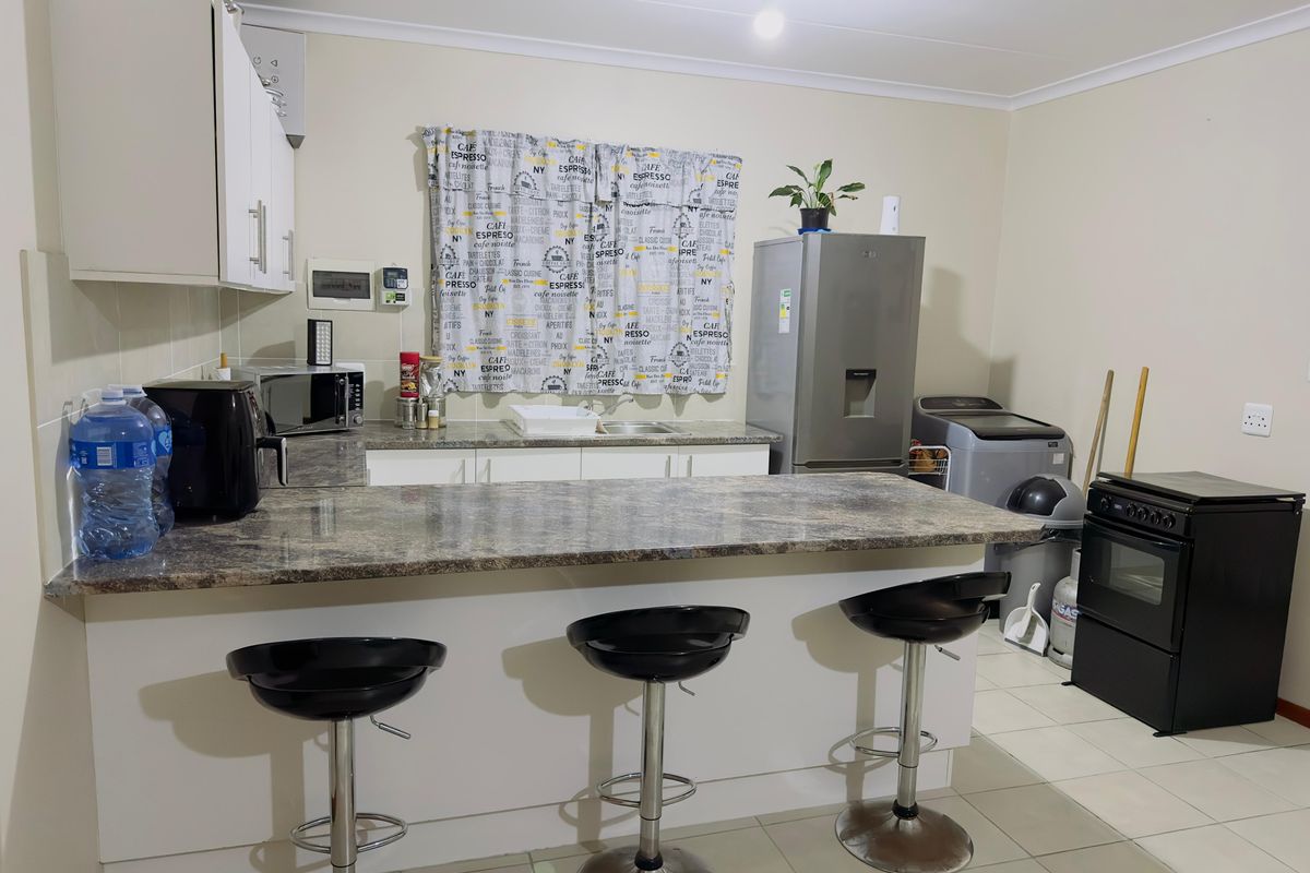 A functional kitchen featuring laminate countertops, built-in cabinetry, and tiled flooring, providing a practical workspace with a breakfast bar area.