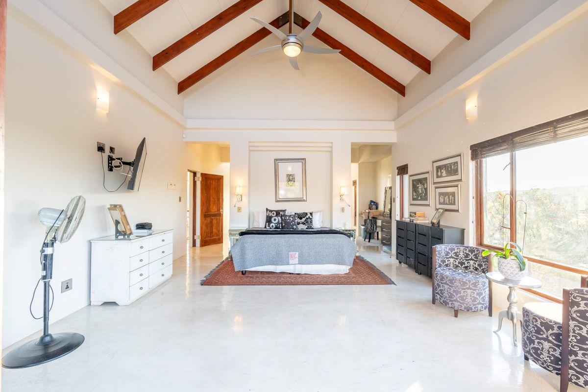 Spacious bedroom featuring a high vaulted ceiling with exposed timber beams, polished concrete floors, and a built-in wall niche for the bed.