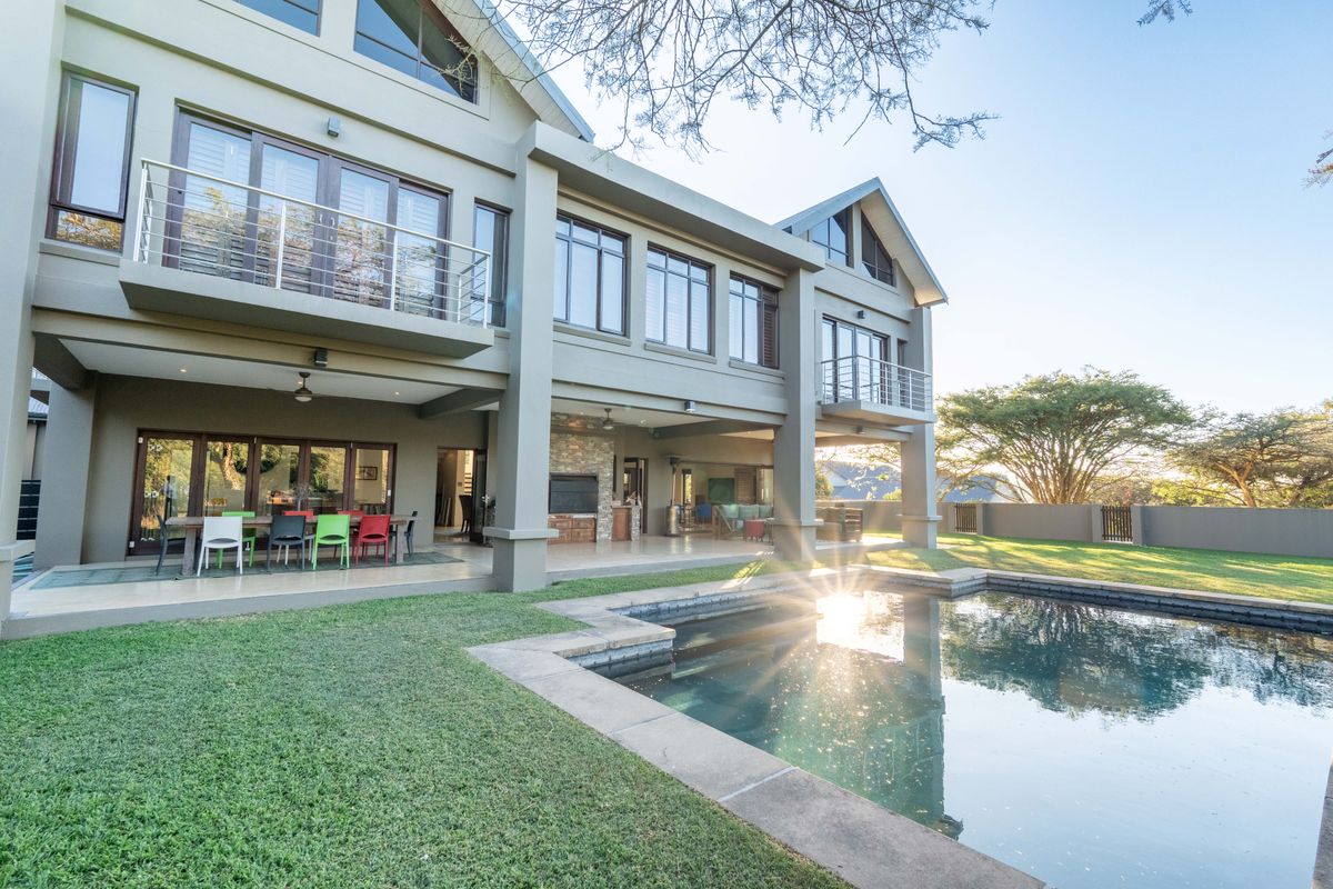 Spacious rear exterior featuring a covered patio, swimming pool, and upper-level balconies, ideal for outdoor entertaining and relaxation.