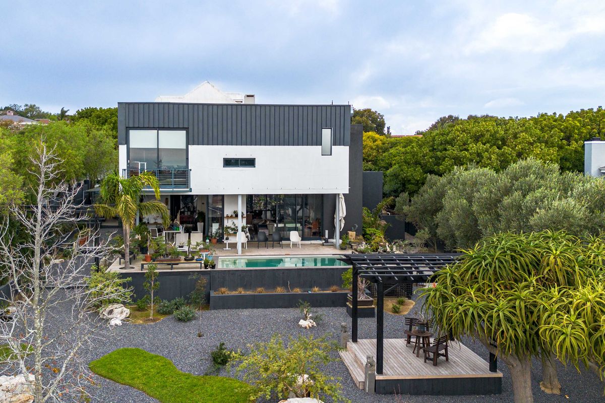 Aerial view of a modern two-story residence featuring a swimming pool, timber deck with pergola, and landscaped garden area.