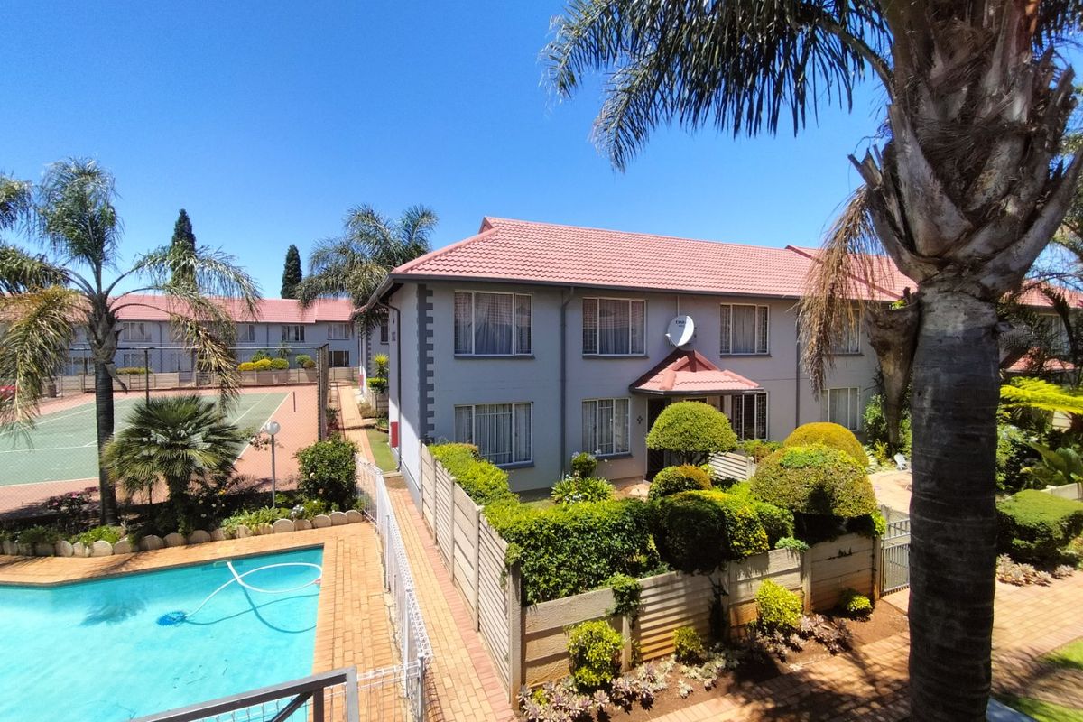 Elevated view of the townhouse complex featuring a swimming pool, tennis court, and well-maintained communal garden areas with mature landscaping.