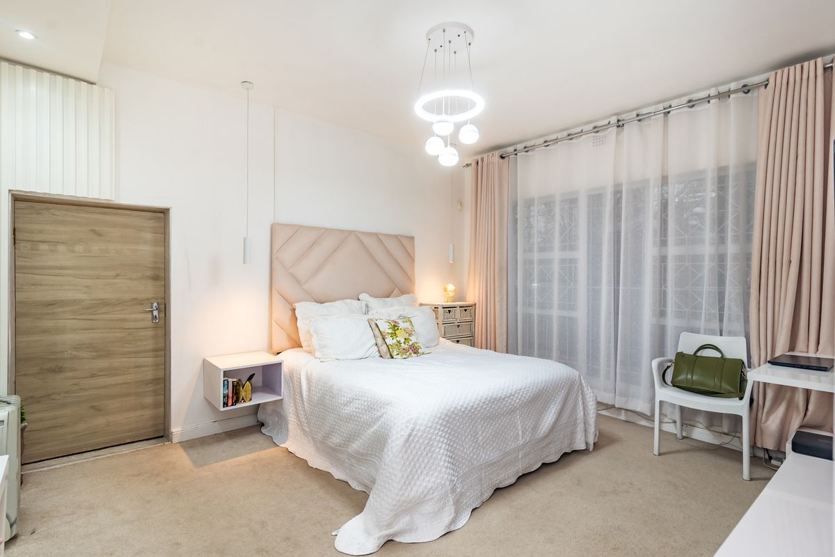 A well-maintained bedroom featuring a custom built-in headboard, floating bedside shelf, modern pendant lighting, and direct access to an outdoor area via sliding doors.