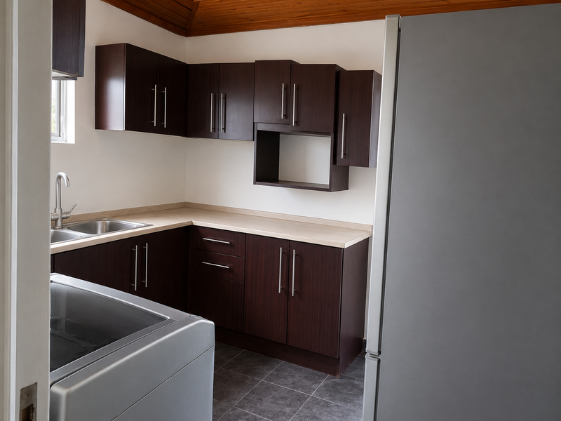 A functional kitchen featuring dark wood cabinetry, laminate countertops, a stainless steel sink, and a timber ceiling.