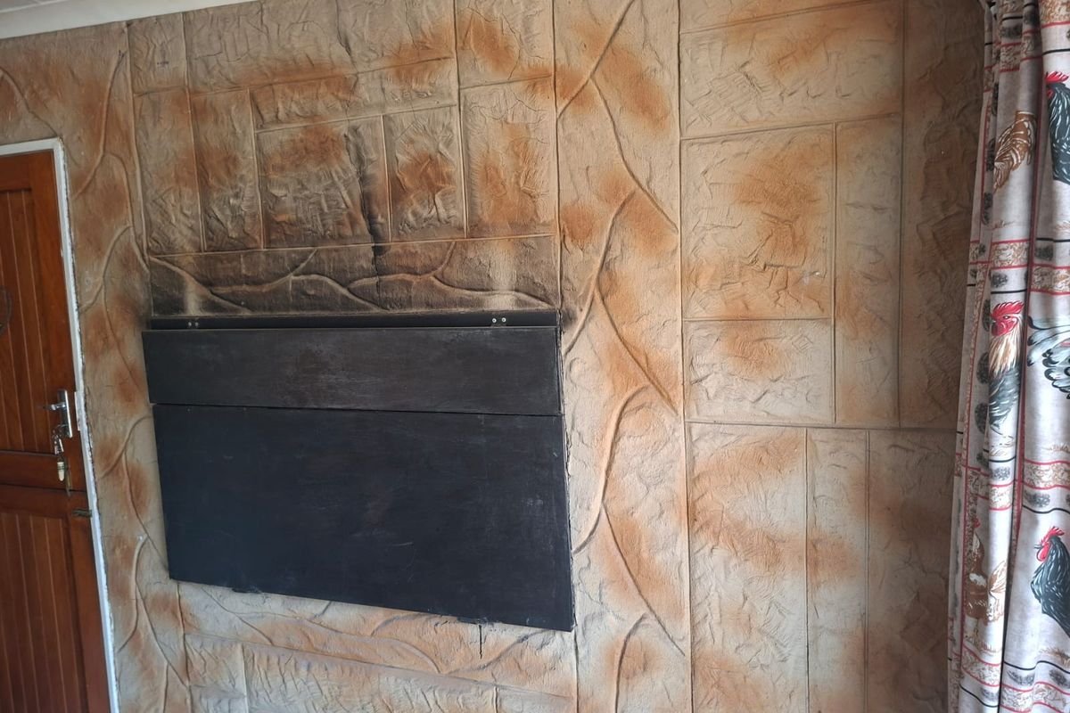 Living area featuring a built-in fireplace with prominent soot staining and textured stone-effect wall cladding.