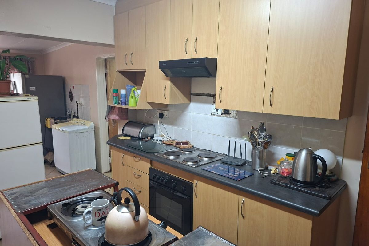 Functional kitchen featuring light wood-tone cabinetry, built-in oven, electric hob, extractor fan, and tiled backsplash with ample storage space.