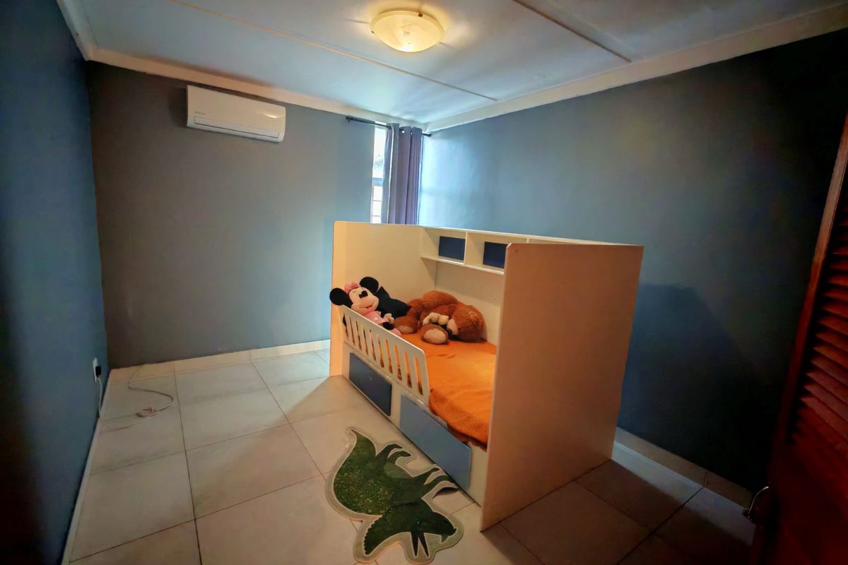 A bedroom featuring tiled flooring, a wall-mounted air conditioning unit, and a ceiling-mounted light fixture.