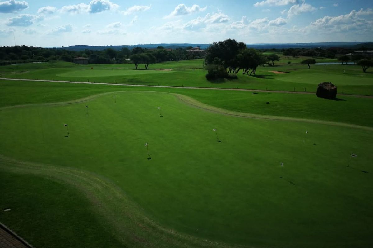 An elevated aerial view of a well-maintained golf course landscape, showcasing expansive green fairways and manicured putting areas.