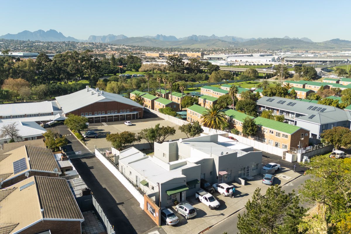 Aerial view of the townhouse complex and surrounding neighborhood, showcasing the property layout, access roads, and proximity to local infrastructure.