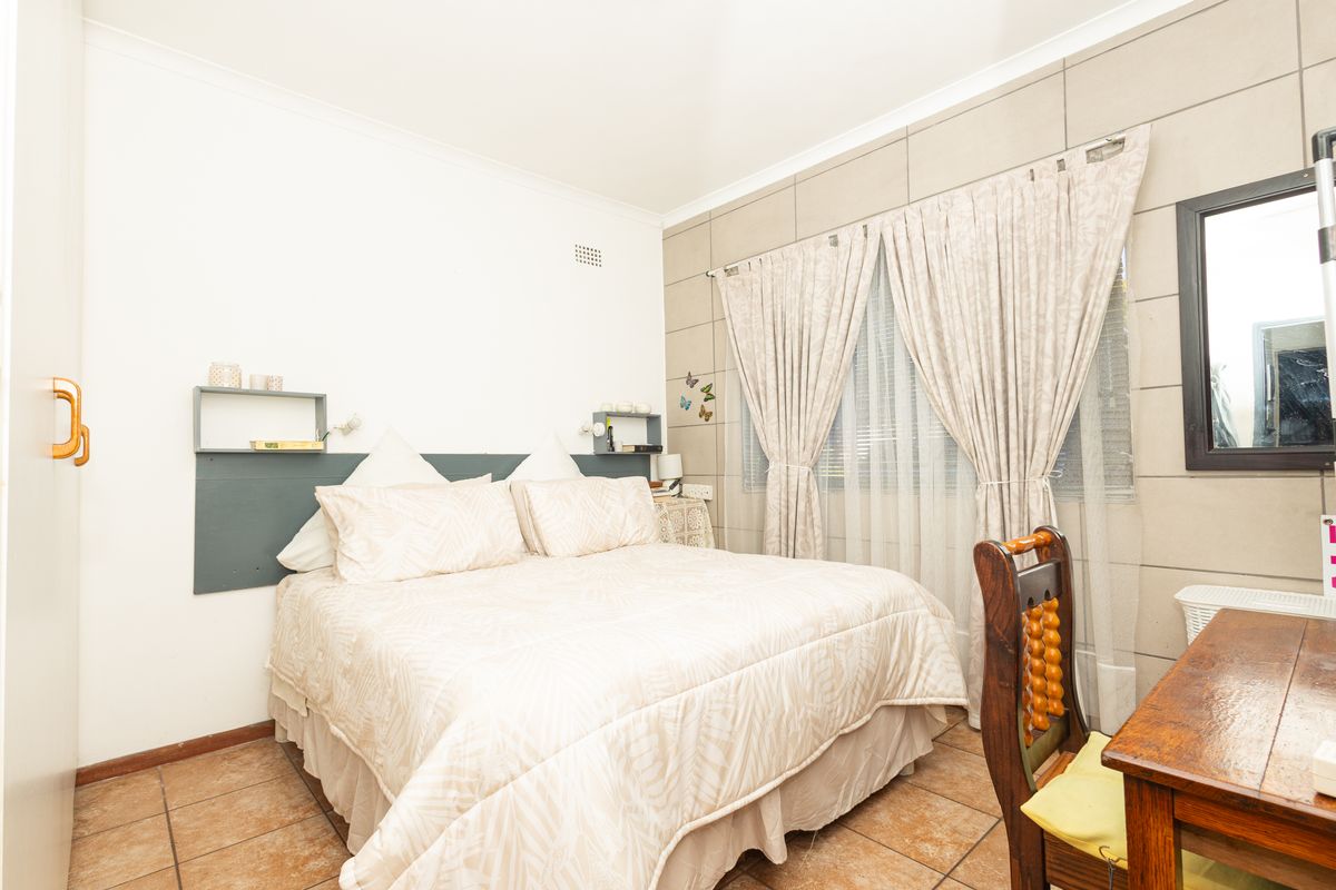 A bedroom featuring tiled flooring, built-in wardrobe storage, and a feature wall with window treatments.