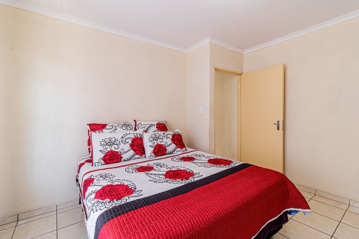 A simple bedroom featuring tiled flooring and neutral wall finishes, providing a functional and clean living space.