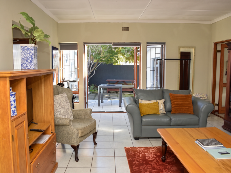 A bright living room featuring tiled flooring and large sliding doors that open onto a paved patio area.