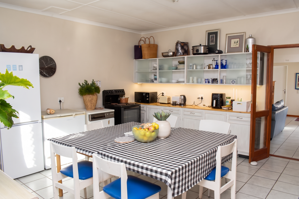 A functional kitchen featuring white cabinetry, under-cabinet lighting, tiled flooring, and a dedicated dining area, providing a practical space for meal preparation and dining.