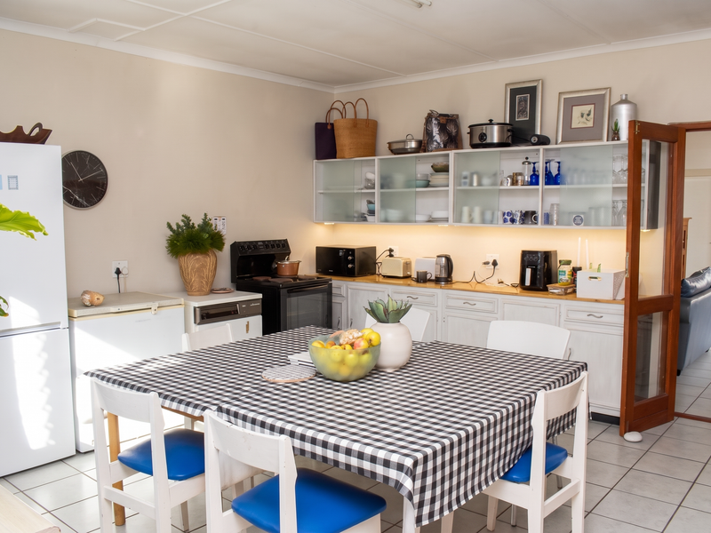A functional kitchen featuring white cabinetry, under-cabinet lighting, tiled flooring, and a dedicated dining area, providing a practical space for meal preparation and dining.