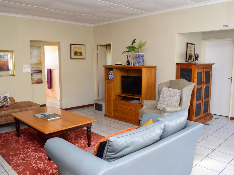 A living room featuring tiled flooring, neutral wall finishes, and access to adjacent rooms, providing a functional and open living space.