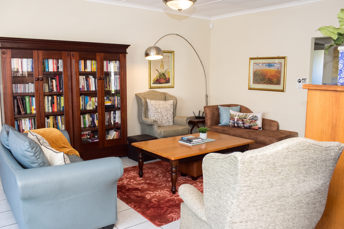 A comfortable living room featuring tiled flooring and a built-in wooden bookshelf, providing a cozy and functional space for relaxation.