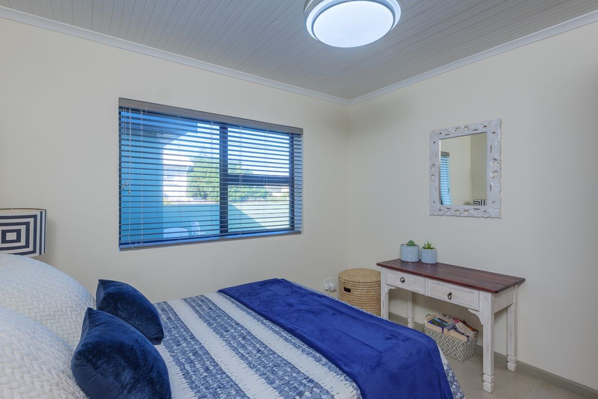 A well-maintained bedroom featuring a tongue and groove ceiling, flush mount lighting, and venetian blinds on the window.