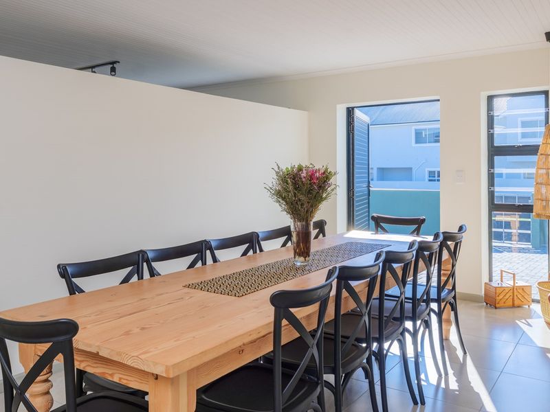 A bright and spacious dining area featuring tiled flooring, a beadboard ceiling, and large windows that provide ample natural light.