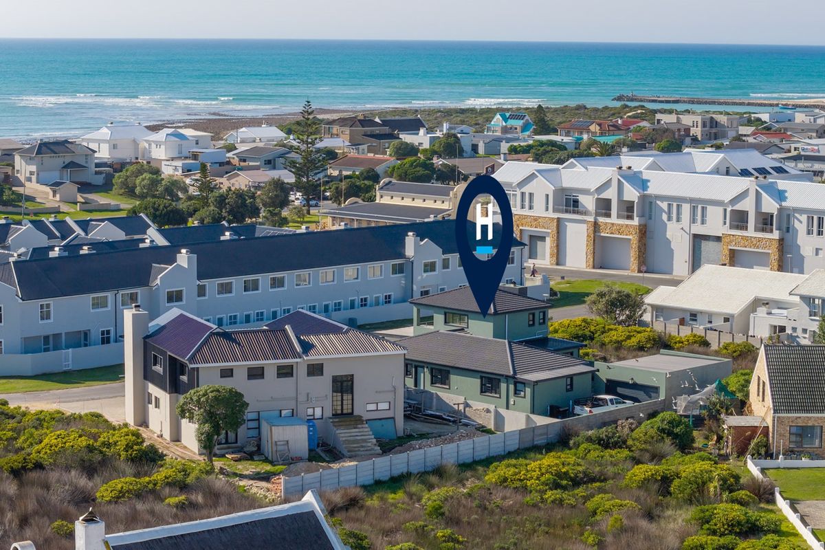 Aerial view of a coastal residential property featuring multi-story homes with tiled roofs, situated near the ocean in a developed neighborhood.