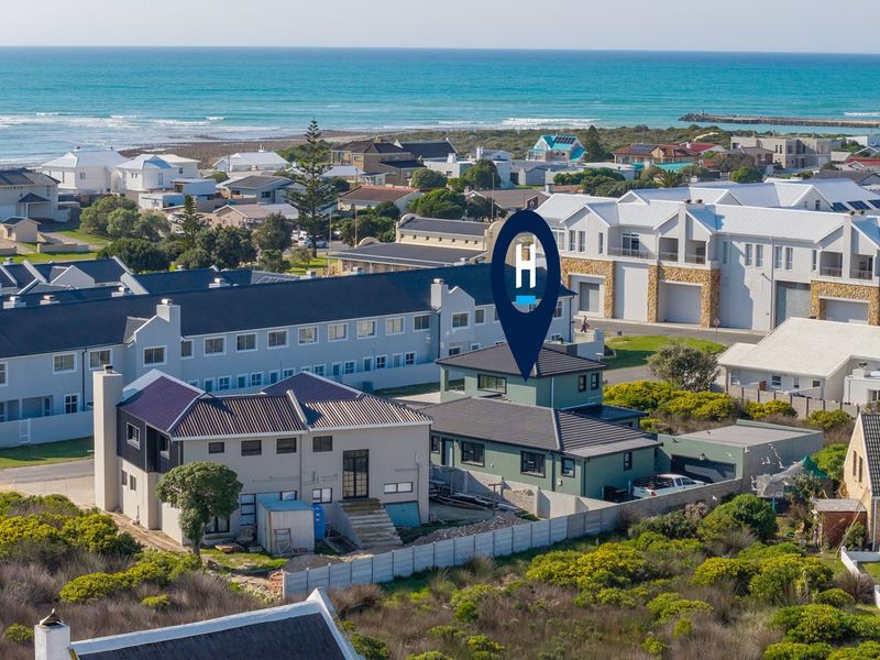 Aerial view of a coastal residential property featuring multi-story homes with tiled roofs, situated near the ocean in a developed neighborhood.