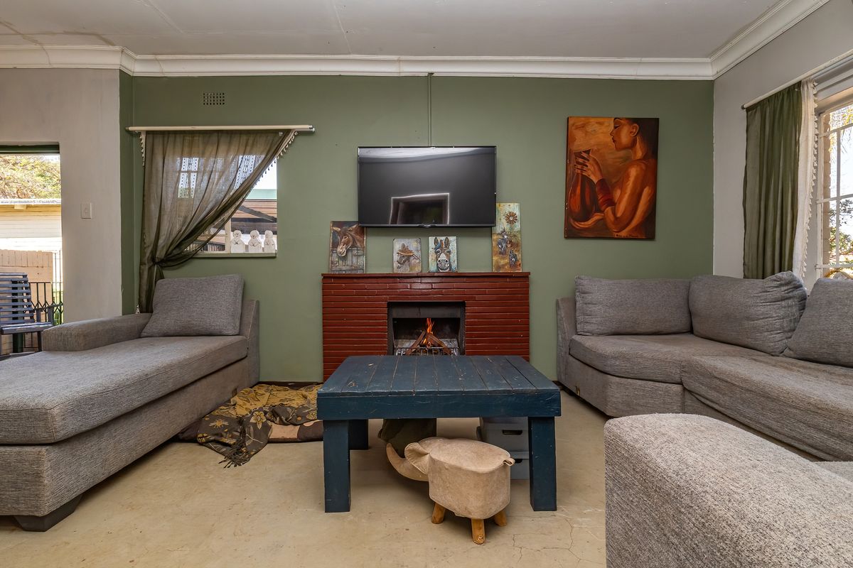 Living room featuring a central brick fireplace, concrete flooring, and large windows allowing natural light into the space.