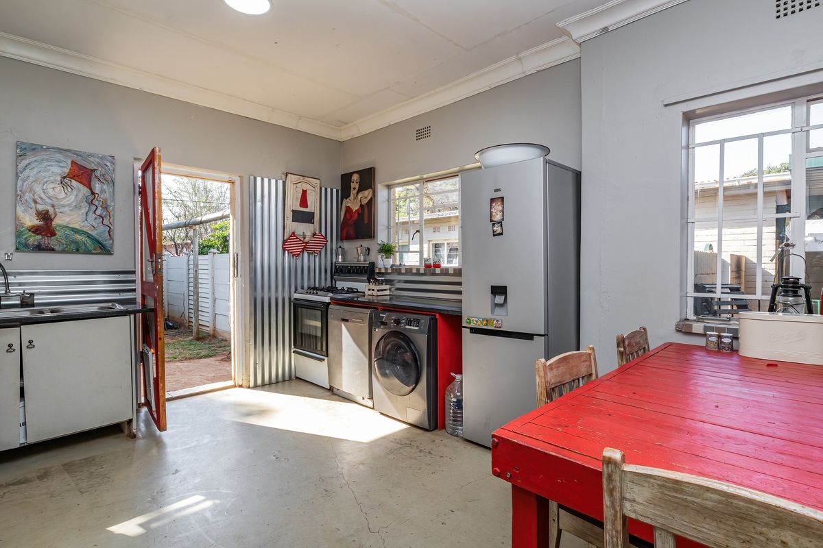 Functional kitchen featuring corrugated metal splashbacks, built-in cabinetry, and direct access to the rear garden area.