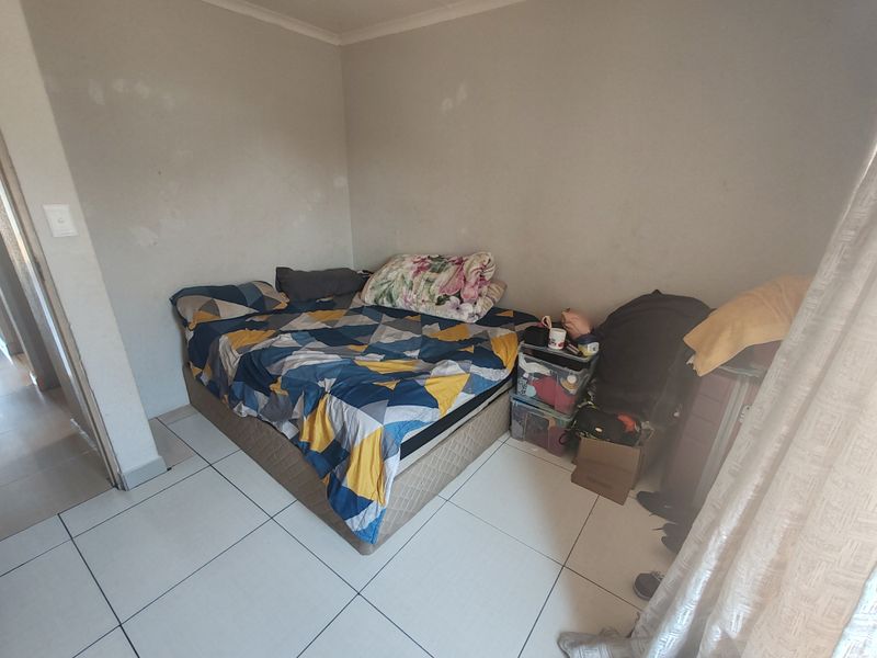 A bedroom featuring tiled flooring and plain walls, currently requiring cosmetic updates to improve the overall aesthetic and finish.