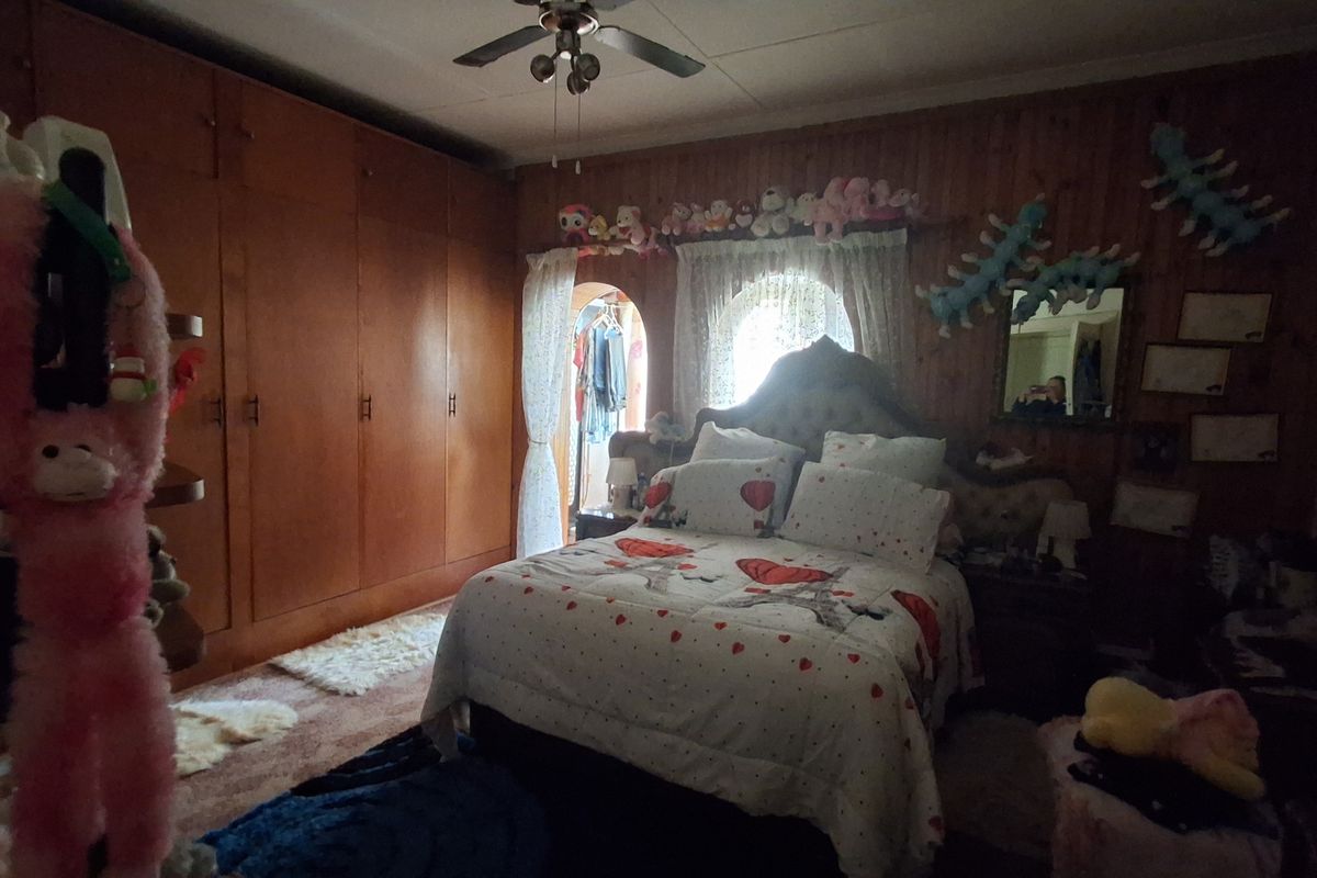 A bedroom featuring extensive built-in wooden cabinetry, wood-paneled walls, and an arched doorway leading to an adjacent space.