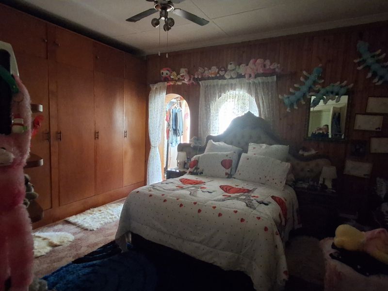 A bedroom featuring extensive built-in wooden cabinetry, wood-paneled walls, and an arched doorway leading to an adjacent space.