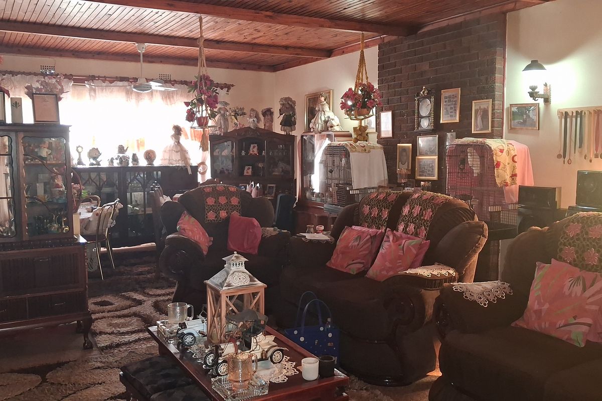 Spacious living room featuring a prominent brick fireplace and exposed timber ceiling, offering a traditional aesthetic with ample room for seating arrangements.