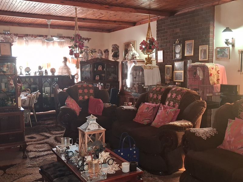 Spacious living room featuring a prominent brick fireplace and exposed timber ceiling, offering a traditional aesthetic with ample room for seating arrangements.