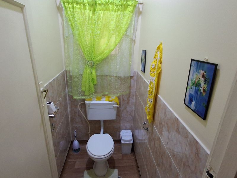 A compact bathroom featuring a standard toilet, half-tiled walls, and wood-look flooring.