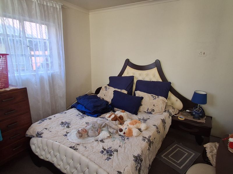 A standard bedroom featuring a window with security bars and neutral wall finishes.