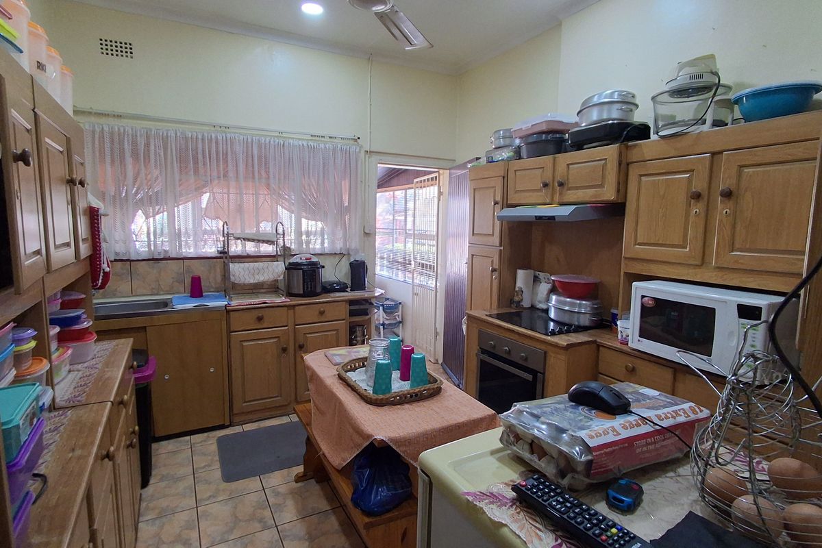 A functional kitchen featuring traditional wooden cabinetry, built-in oven, hob, and extractor fan with direct access to an outdoor area.