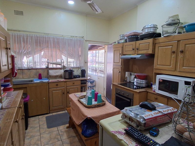 A functional kitchen featuring traditional wooden cabinetry, built-in oven, hob, and extractor fan with direct access to an outdoor area.